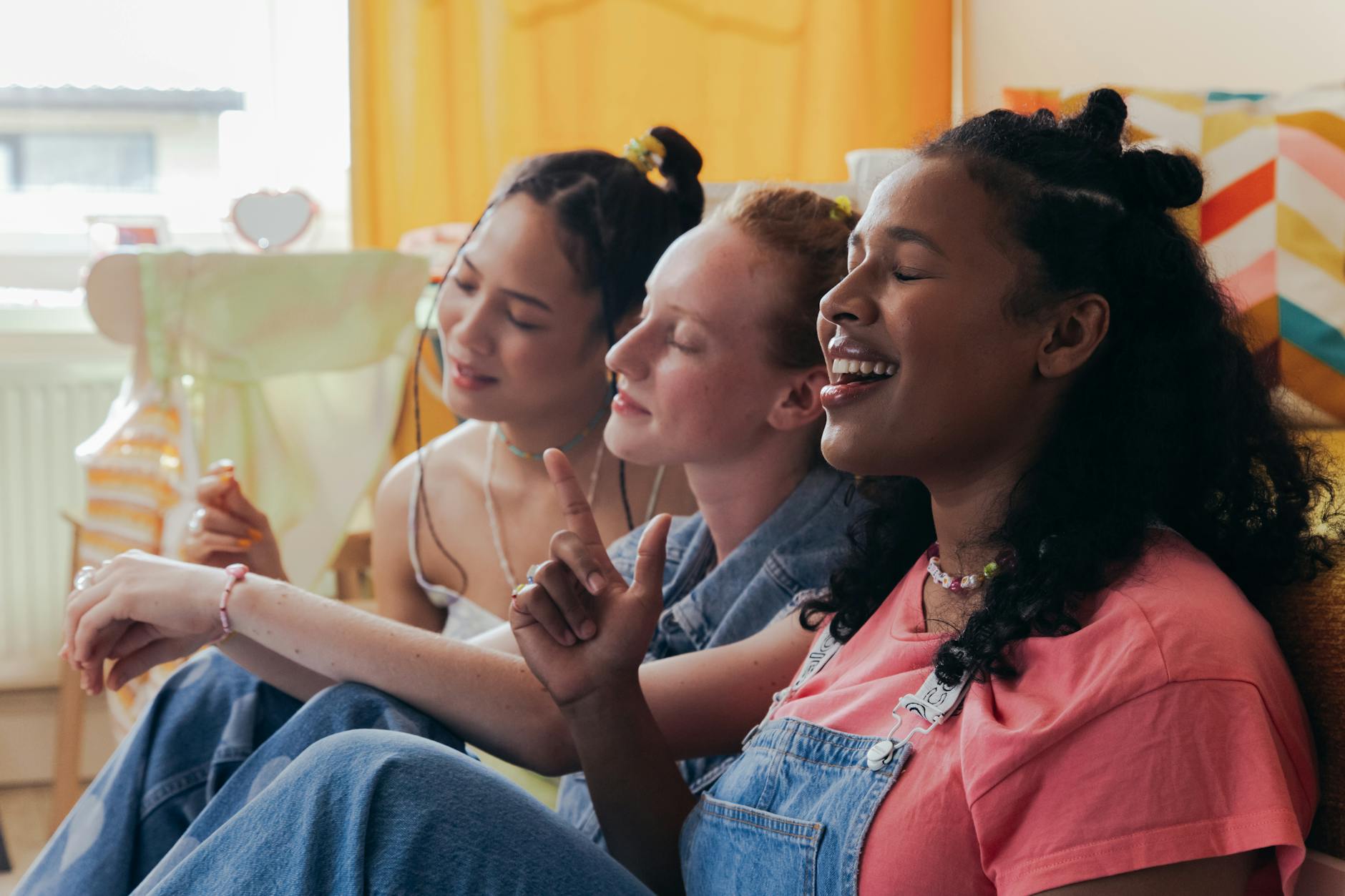 Three diverse women enjoying a relaxed bonding time indoors, sitting and smiling.