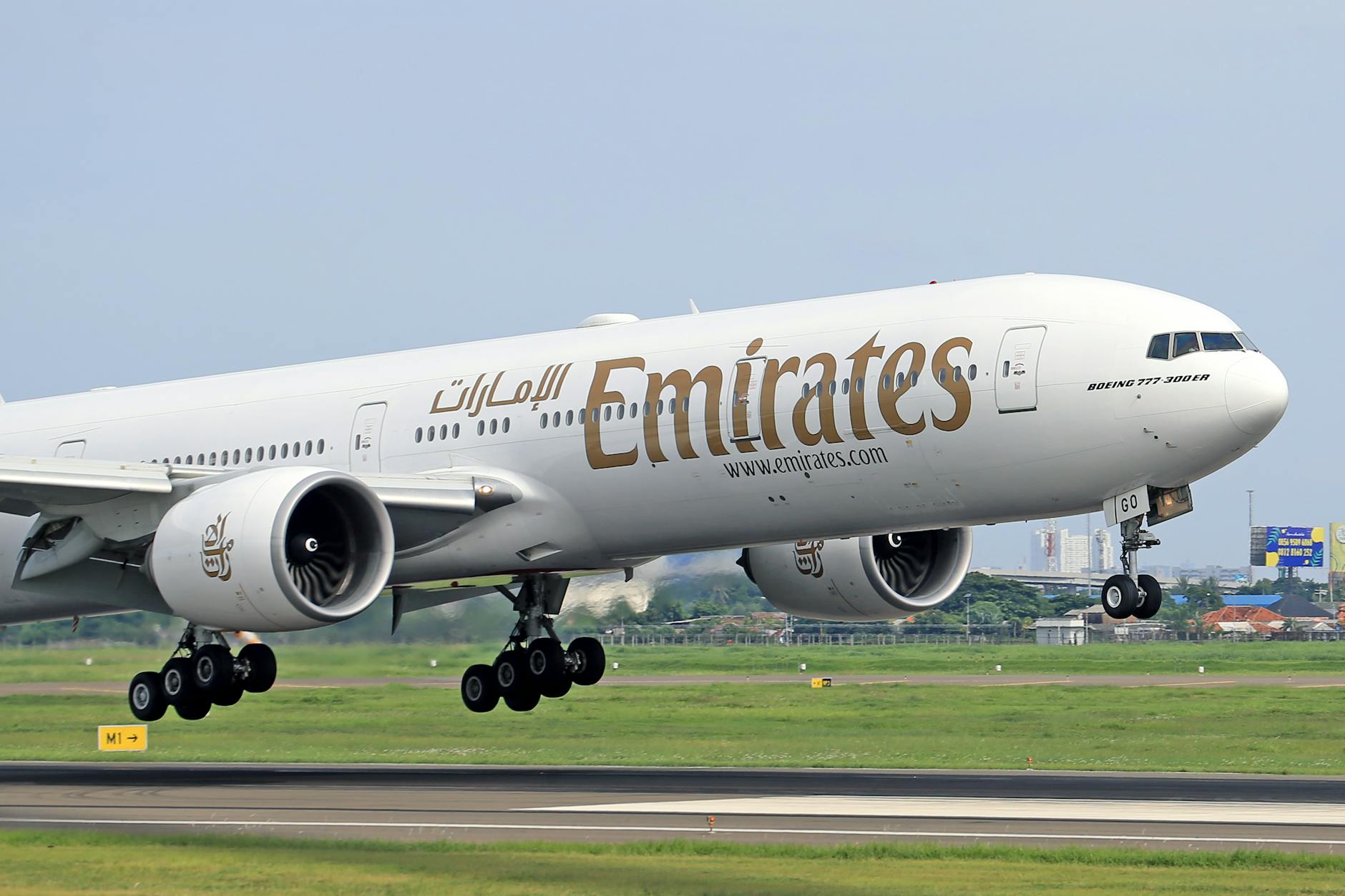 Emirates Boeing 777-300ER aircraft touching down on runway on a clear day.