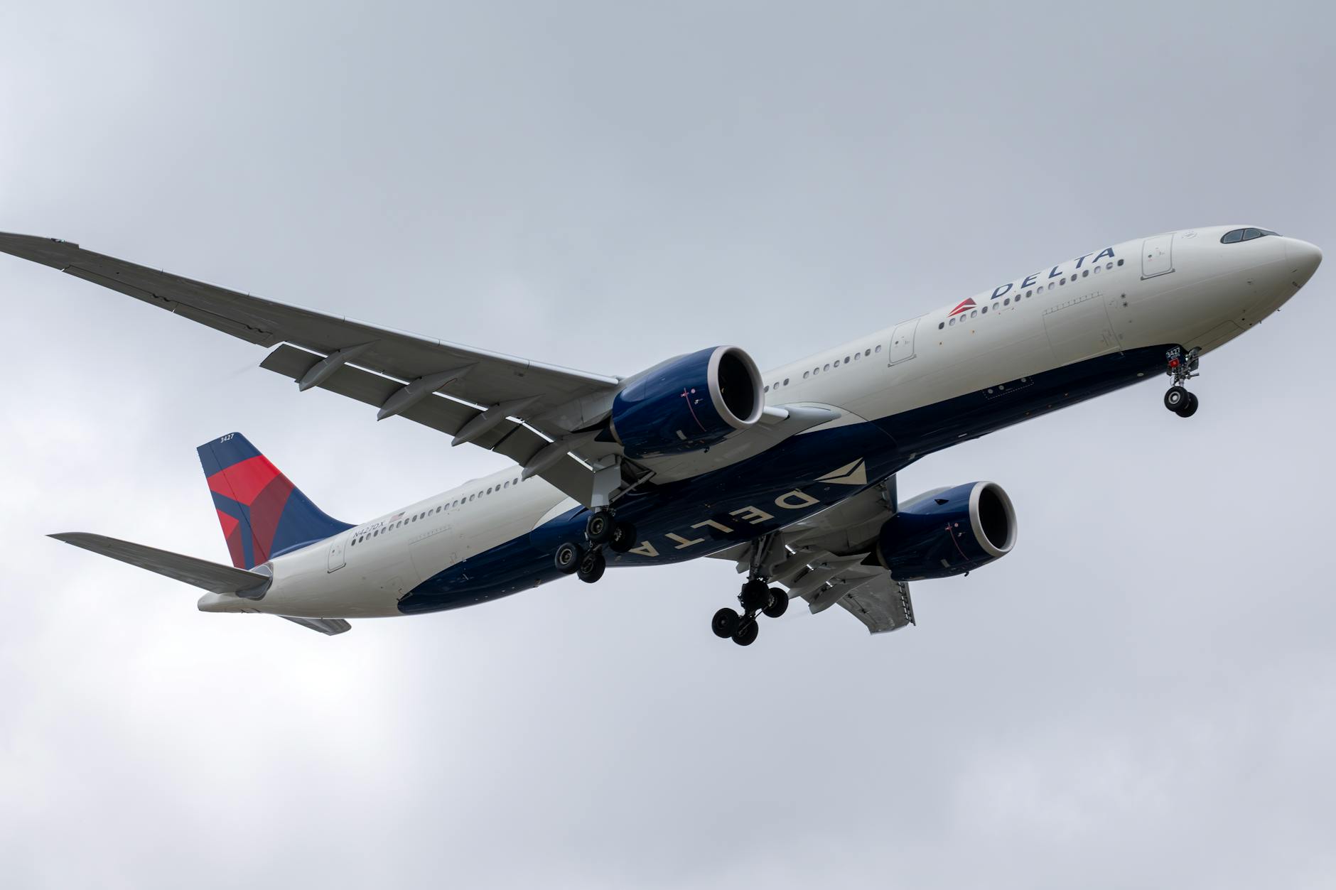 Delta Airlines aircraft in descent over Los Angeles, cloudy sky.
