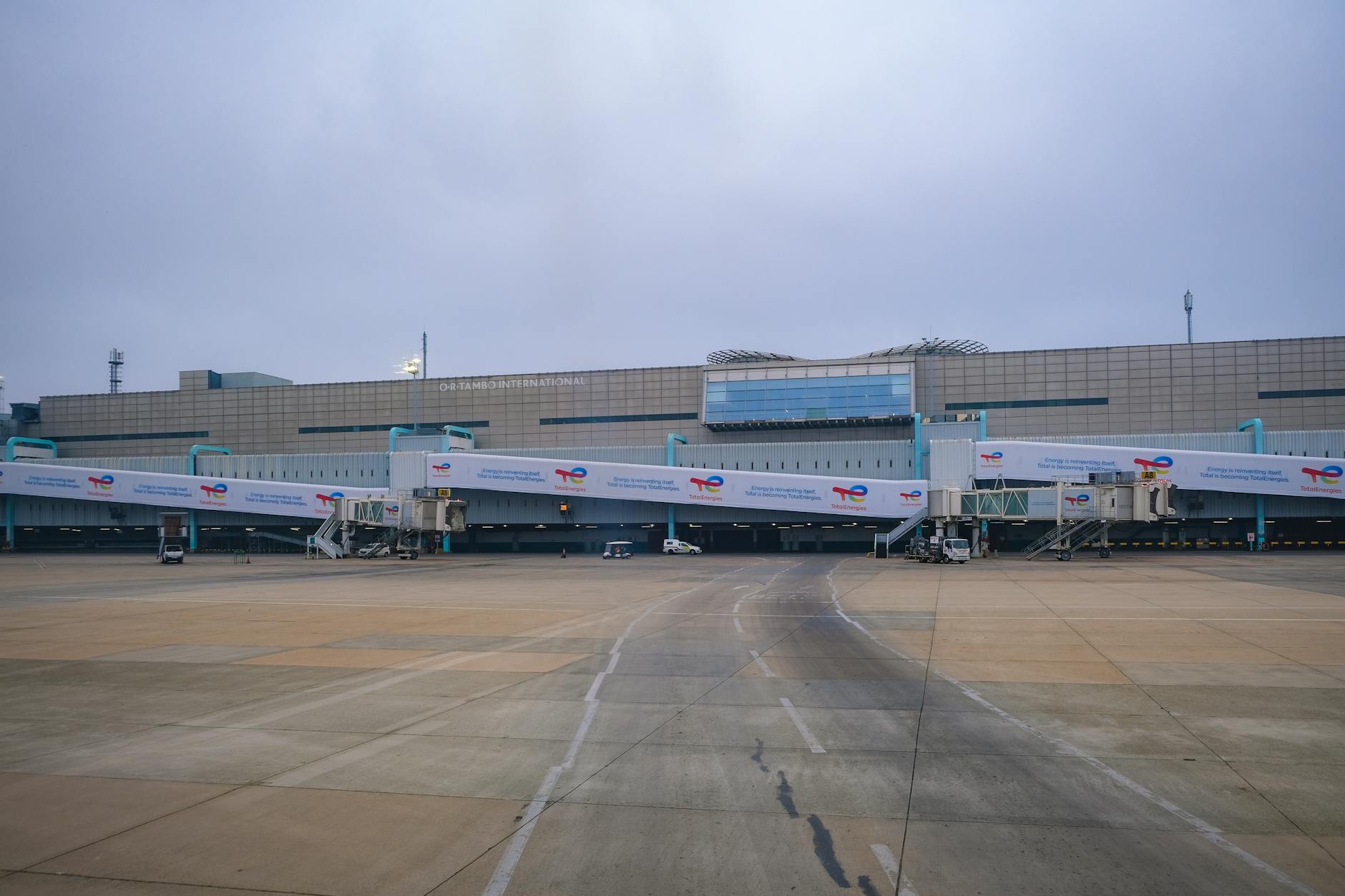 View of a modern airport terminal with jet bridges leading to the runway.